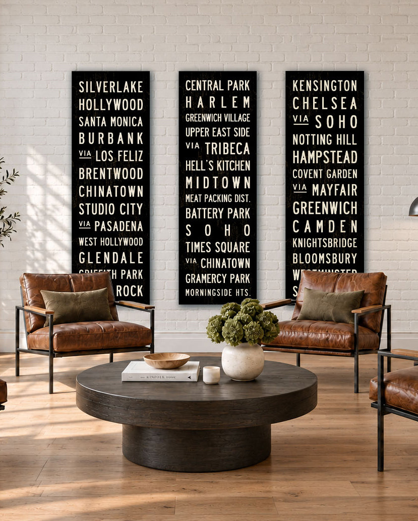 Three Subway Sign Art canvases hanging in a modern loft with leather chairs and a coffee table.