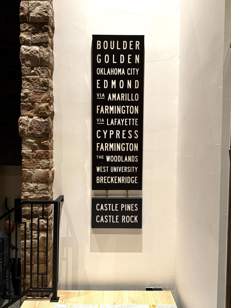 Custom Subway Sign by Transit Design hanging on a white wall next to a stone column.